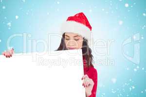 Composite image of beauty brunette in santa hat showing white po