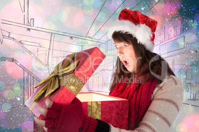 Composite image of shocked festive brunette opening a gift