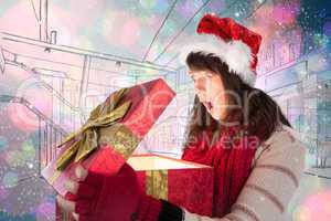 Composite image of shocked festive brunette opening a gift