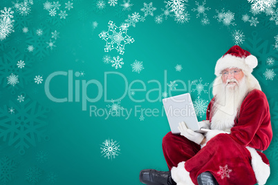 Composite image of santa sits and uses a laptop