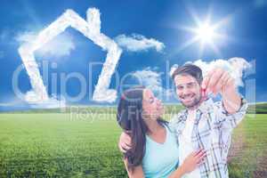 Composite image of happy young couple showing new house key