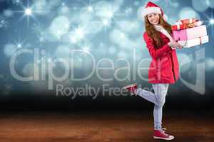 Composite image of festive redhead holding pile of gifts