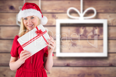 Composite image of festive blonde holding a gift