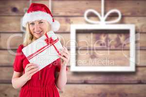 Composite image of festive blonde holding a gift