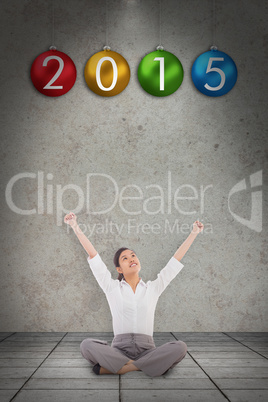 Composite image of cheering businesswoman sitting cross legged