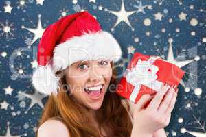 Composite image of festive redhead holding a gift