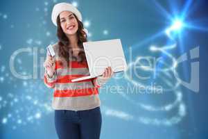 Composite image of festive brunette holding laptop and credit ca