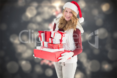 Composite image of festive blonde holding pile of gifts