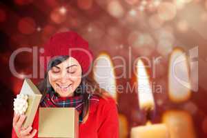 Composite image of happy brunette opening christmas gift