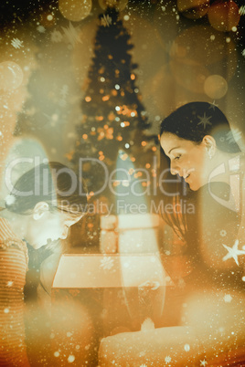 Composite image of festive mother and daughter opening a glowing