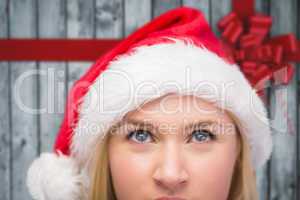 Composite image of festive blonde looking up in santa hat