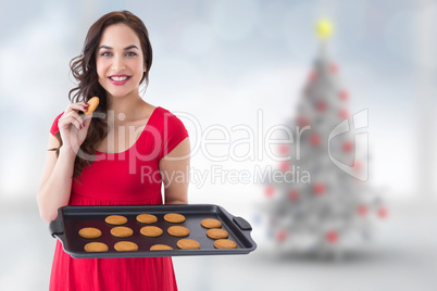 Composite image of happy brunette eating hot cookies