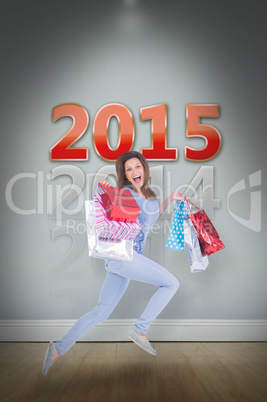 Composite image of excited brunette jumping while holding shoppi
