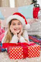 Composite image of festive little girl smiling at camera with gift