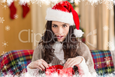 Composite image of surprised brunette opening gift bag at chistm