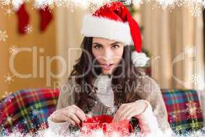 Composite image of surprised brunette opening gift bag at chistm