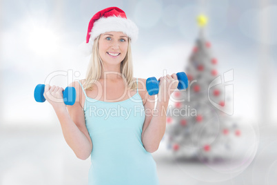 Composite image of festive fit blonde holding dumbbells