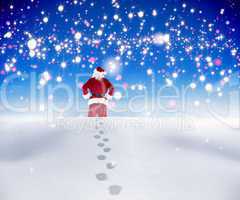 Composite image of santa walking in the snow