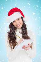 Composite image of smiling brunette writing her christmas list