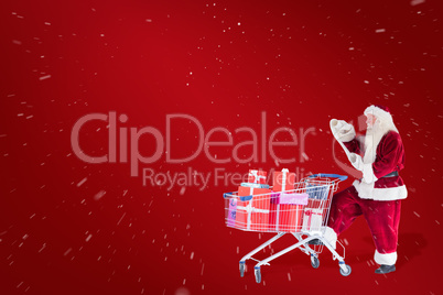 Composite image of santa pushes a shopping cart while reading