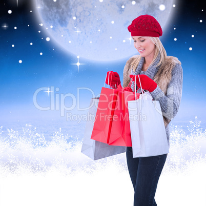 Composite image of blonde in winter clothes with shopping bags