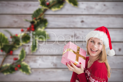 Composite image of woman smiling with present in hands