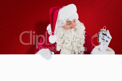 Composite image of happy santa holding alarm clock and sign