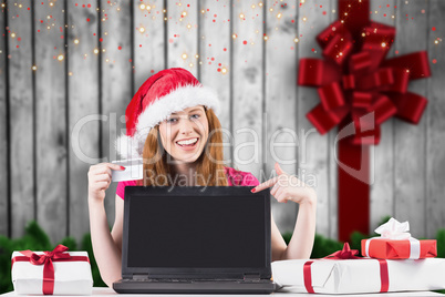 Composite image of festive redhead shopping online with laptop