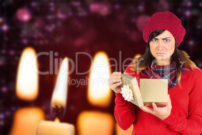 Composite image of unhappy brunette opening christmas gift