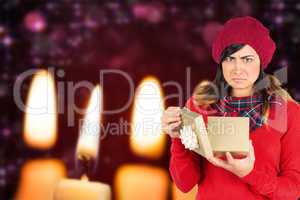 Composite image of unhappy brunette opening christmas gift