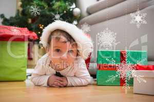 Composite image of cute baby boy lying on floor at christmas