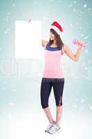 Composite image of festive fit brunette holding poster with dumb