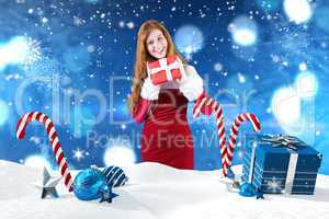 Composite image of festive redhead holding a gift