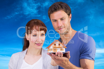 Composite image of couple holding a model house