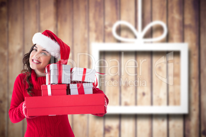 Composite image of festive brunette holding pile of gifts