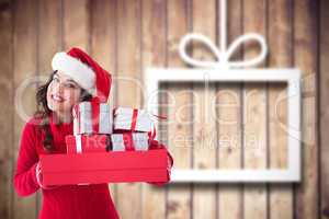 Composite image of festive brunette holding pile of gifts