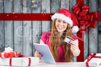 Composite image of festive redhead shopping online with tablet