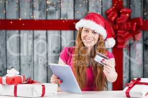 Composite image of festive redhead shopping online with tablet