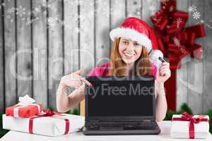 Composite image of festive redhead shopping online with laptop