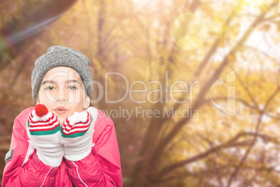 Composite image of wrapped up little girl blowing over hands