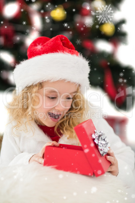 Composite image of festive little girl looking at gift