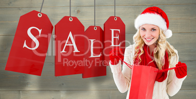 Composite image of happy festive blonde with shopping bag