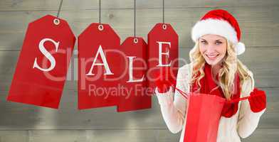 Composite image of happy festive blonde with shopping bag