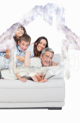 Composite image of children lying on their parents on sofa