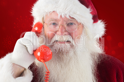 Composite image of santa on his red phone