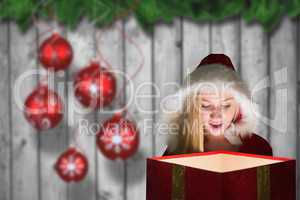 Composite image of festive blonde looking into glowing gift