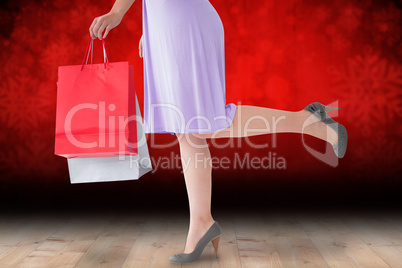 Composite image of mid section of woman in dress holding shoppin