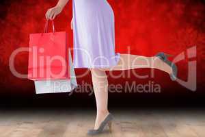 Composite image of mid section of woman in dress holding shoppin