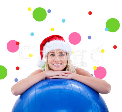 Composite image of festive fit blonde leaning on exercise ball