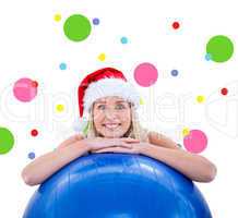 Composite image of festive fit blonde leaning on exercise ball